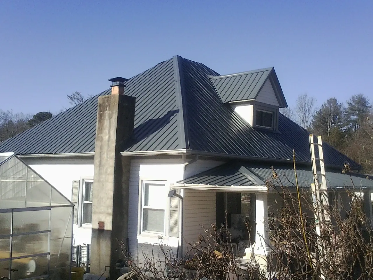 Dark blue standing seam metal roof on a white farmhouse with dormer — Slate & Tile Roof Repair by Roofing Brothers in Wilmerding