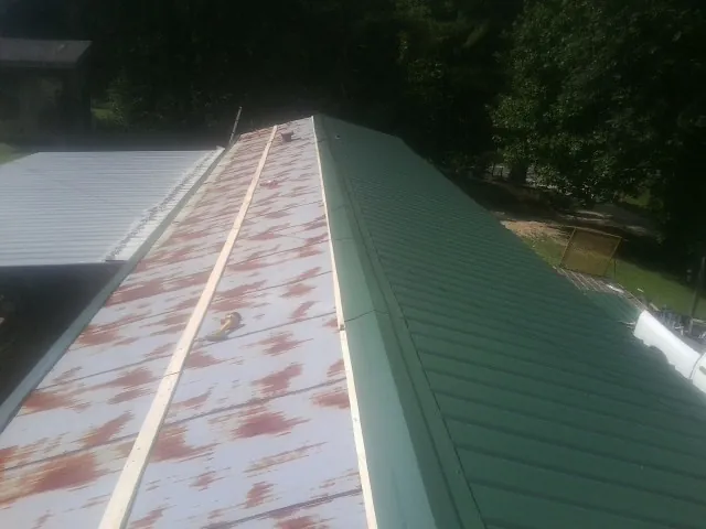 Old rusted panels beside newly installed green metal roofing — Wind Damage Roof Repair by Roofing Brothers in Wilmerding