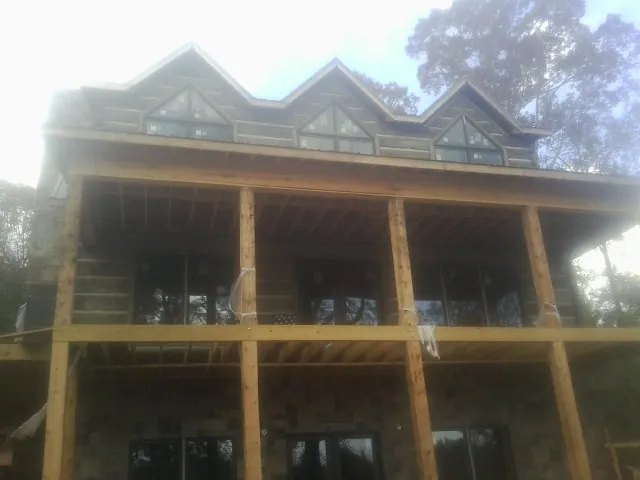 Dormers and porch framing on a large log home under construction — Roof Coating work by our crew in Wilmerding