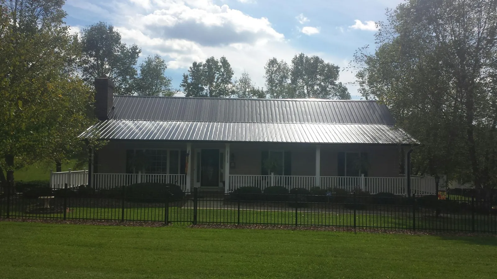 Gray metal roof on a brick ranch with a full width front porch — Gutter Guard Installation work by our crew in Wilmerding