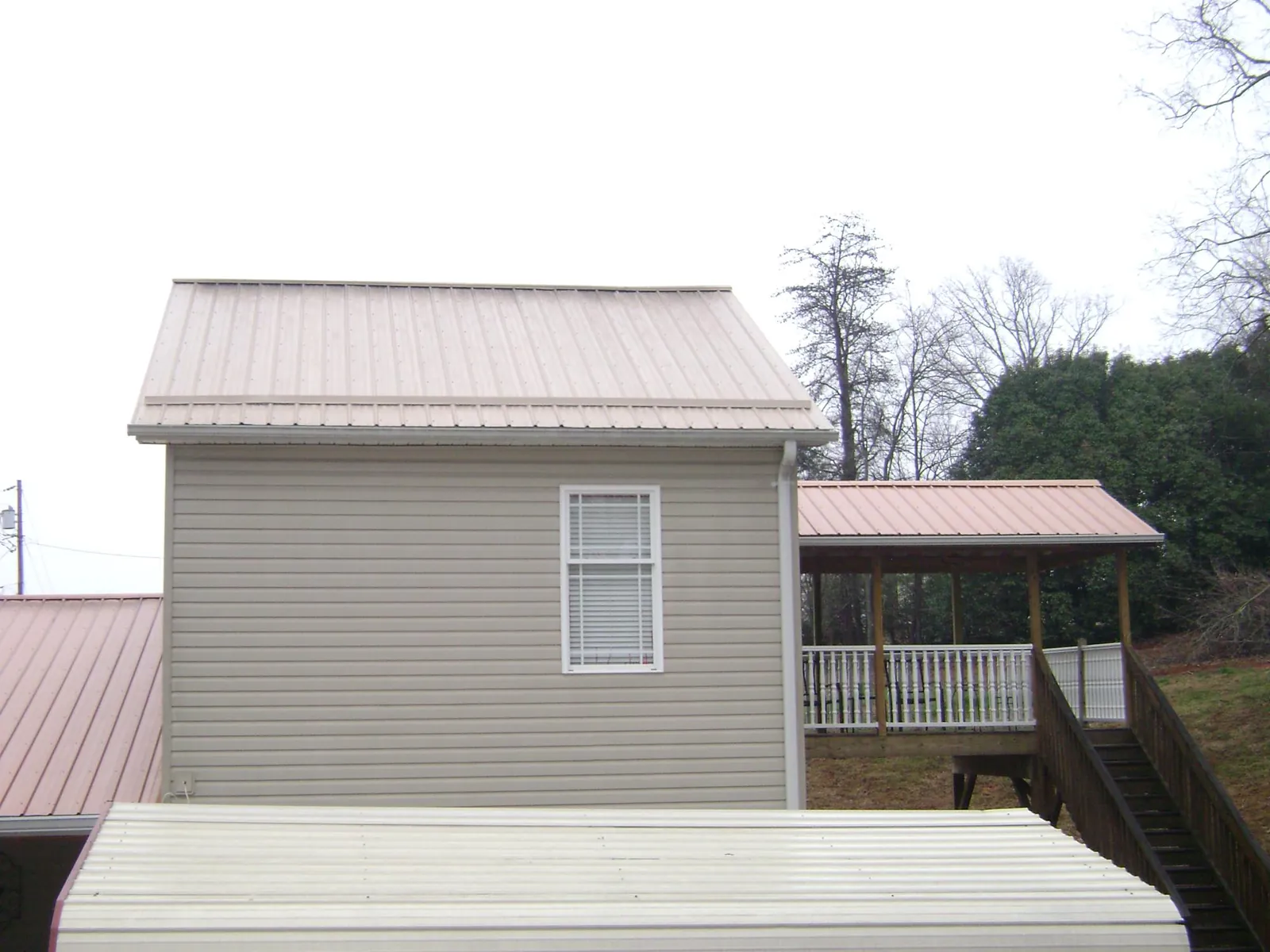 Tan metal roofs on a two story addition and attached porch, from a Roof Replacement job in Wilmerding