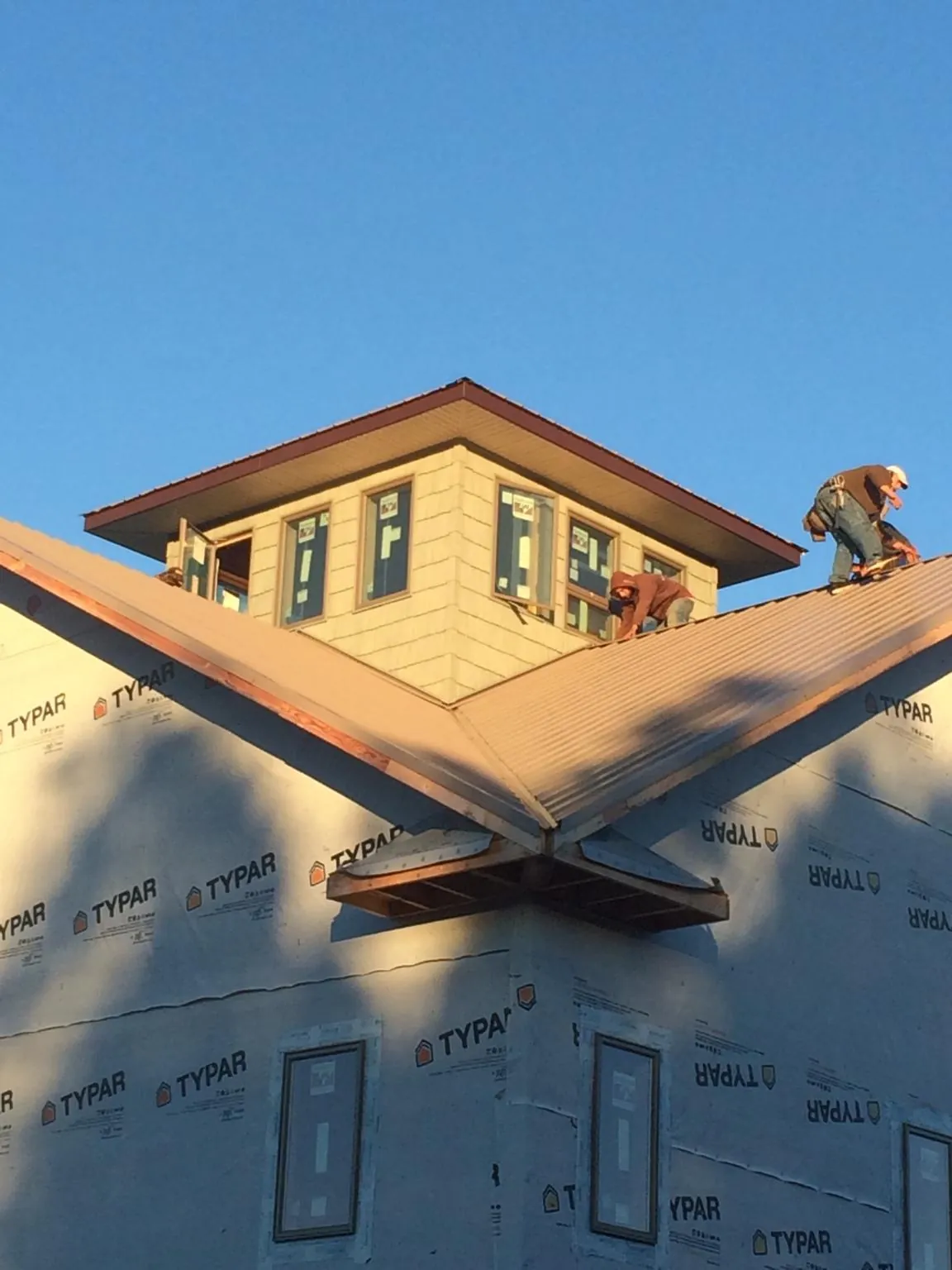 Roofers working around a rooftop cupola on a new metal roof at sunset — Roof Waterproofing in Wilmerding by Roofing Brothers